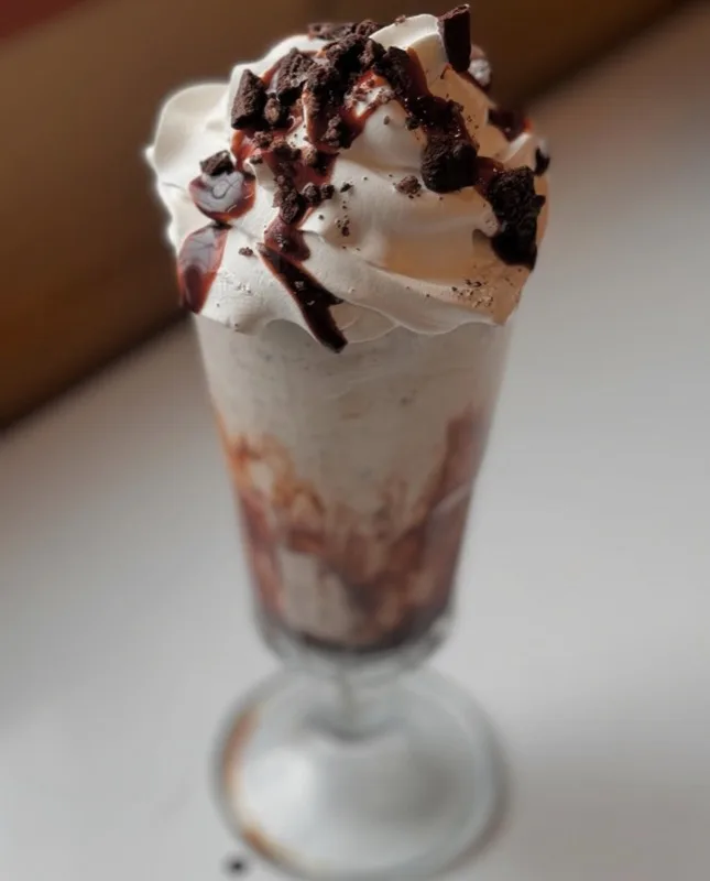 Oreo milkshake topped with whipped cream and chocolate syrup